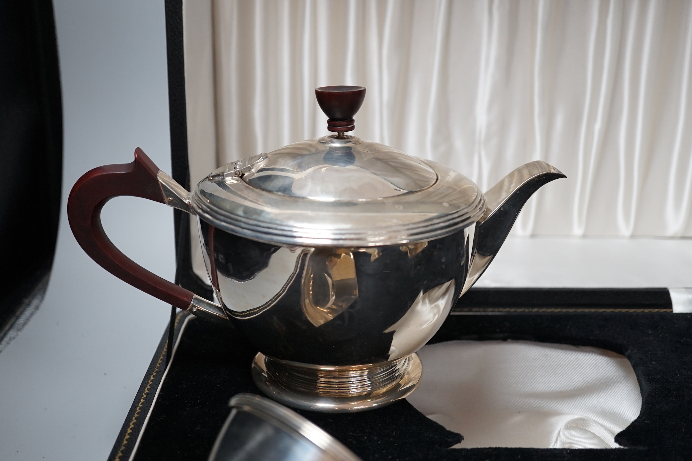 A cased Elizabeth II three piece silver tea set, Adie Bros. Birmingham, 1960, gross 23.7oz, with a plated teapot stand.